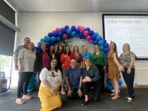 3 event attendees stood under a balloon arch