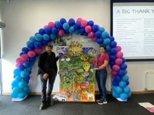 3 event attendees stood under a balloon arch
