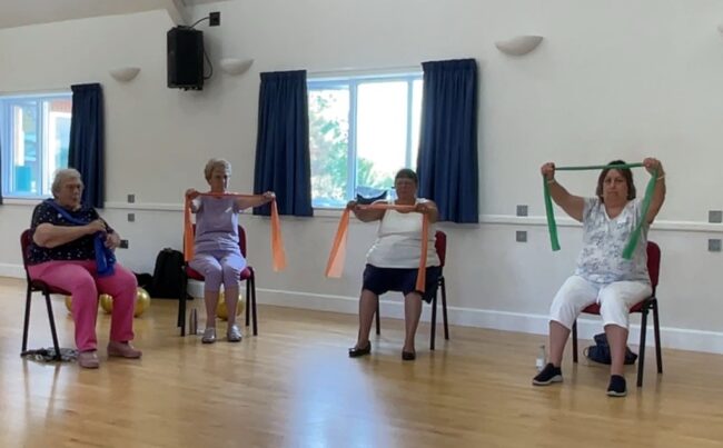 4 ladies doing seated exercises with resistance bands.
