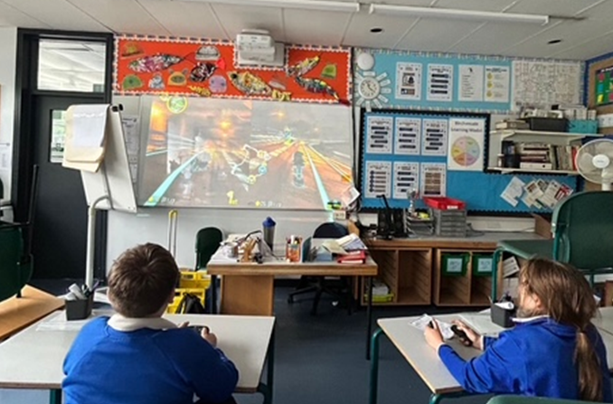 children playing gaming on screen at school youth club