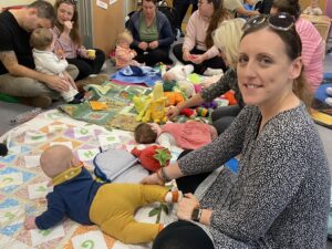 a woman sat down with her baby on her tummy on a mat